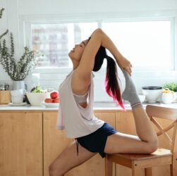 young asian woman stretching leg on wooden chair
